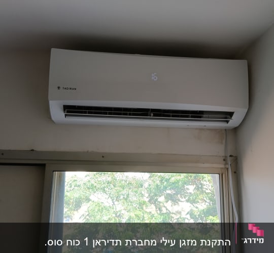 מזגן קיר לבן מותקן מעל חלון